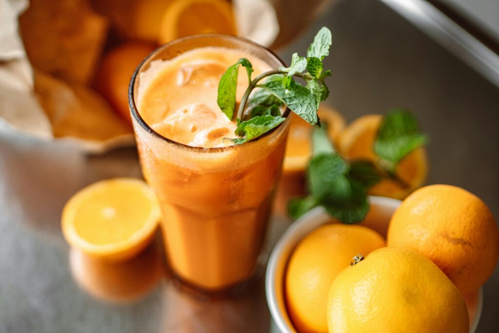 Orange juice garnished with mint surrounded by fresh oranges, perfect for a healthy refreshment.